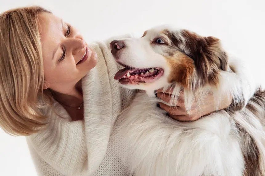 A happy dog owner embracing her Australian Shepherd